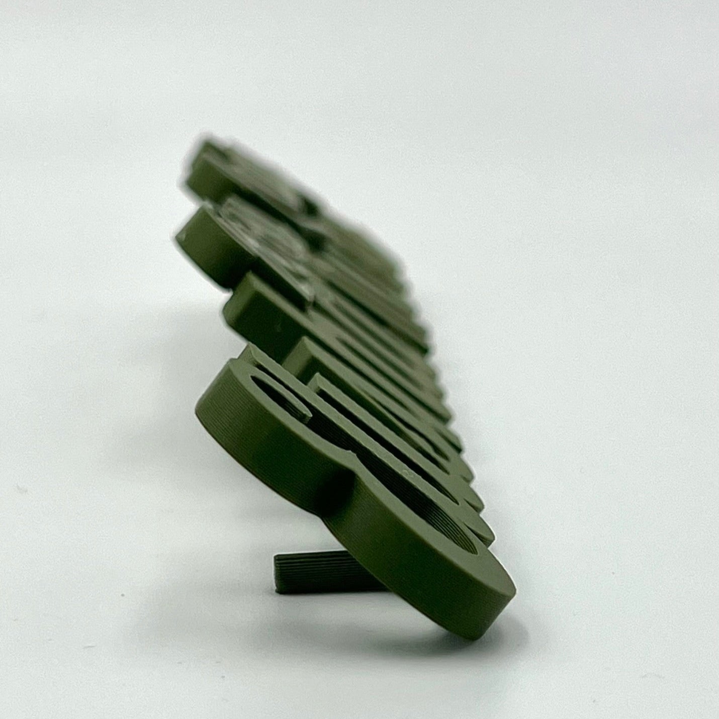 A close-up side view of several green 3D-printed desk names, showing their depth and texture.