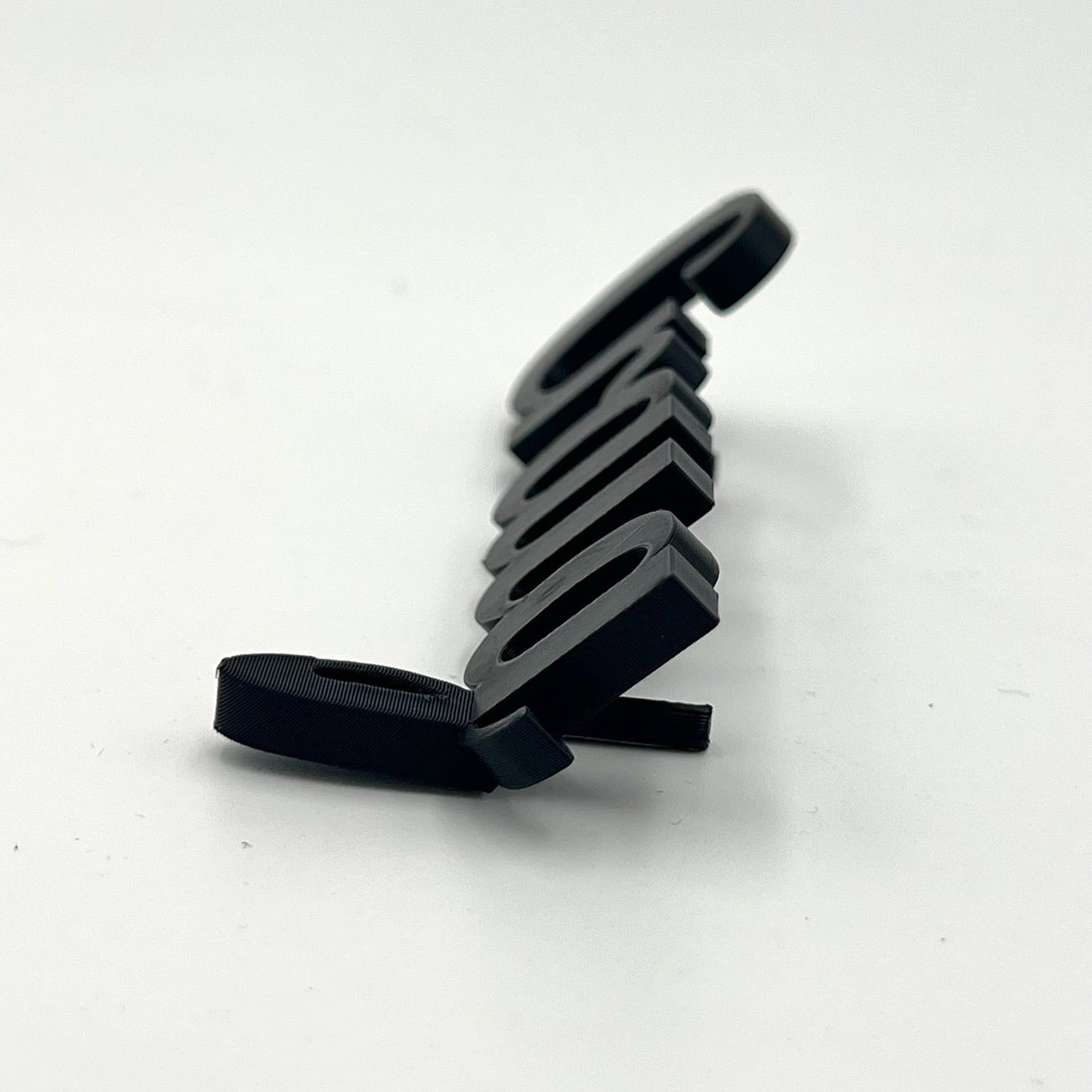 A side-view close-up of a black 3D printed personalised place name spelling "Craig" resting on a plain white surface. The three-dimensional nature of the lettering and its thickness are visible.
